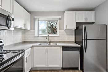 A kitchen with white cabinets and a stainless steel refrigerator.